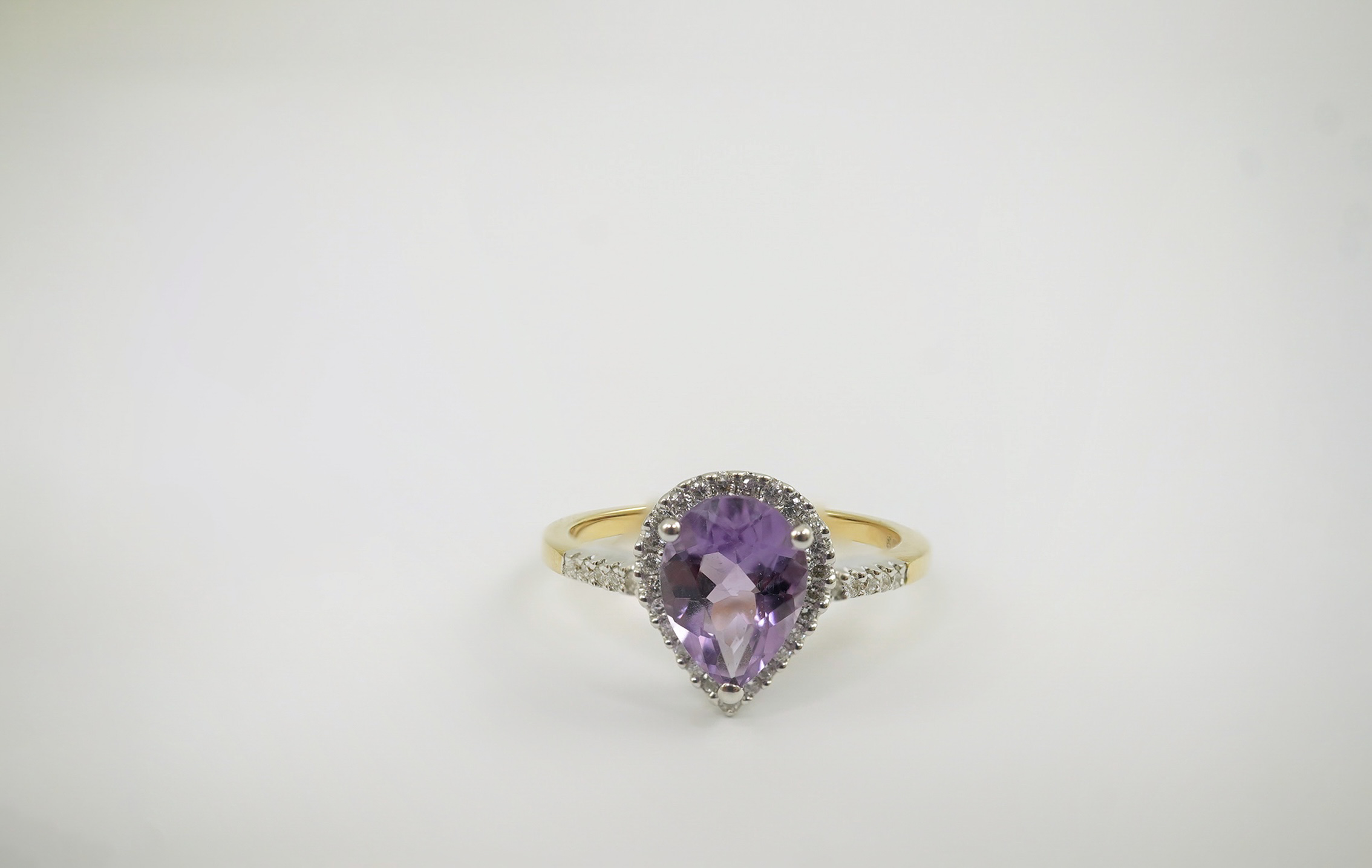 A modern 18ct gold and single stone pear cut amethyst set ring, with diamond chip set border and shoulders